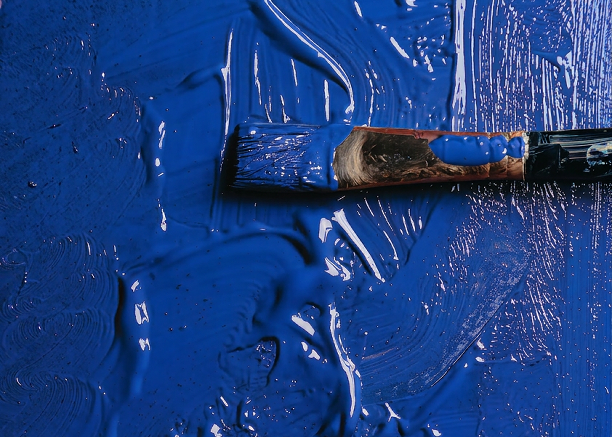 Close-up of a brush with blue paint on a blue background